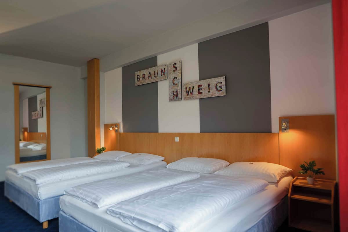 A hotel room with two beds, a mirror, and a wall with decorative signs.