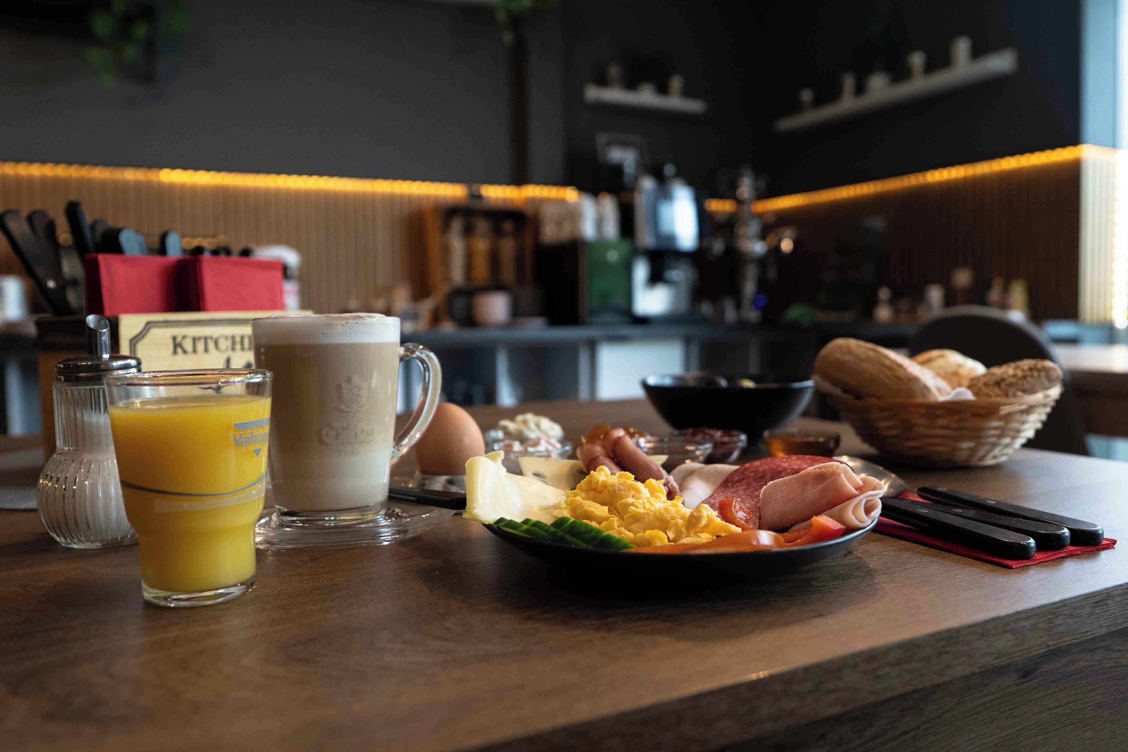 A breakfast setting with a plate of eggs, ham, and toast, a glass of orange juice, and a cup of coffee.