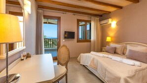Ein Hotelzimmer mit Bett, Schreibtisch, Stuhl, Fernseher und einem Balkon mit Vorhängen.