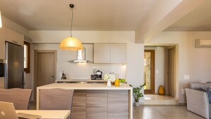 Eine moderne Küche mit Kochinsel, ein Essbereich mit Laptop und ein Wohnzimmer mit Sofa.