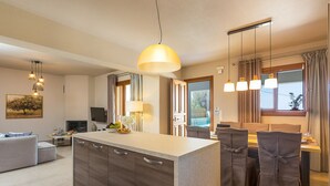 Eine moderne Küche mit Kochinsel, Essbereich mit Stühlen und ein Wohnzimmer mit Sofa.