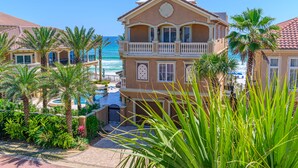 Un hotel frente a la playa con piscina, palmeras y vistas al océano.