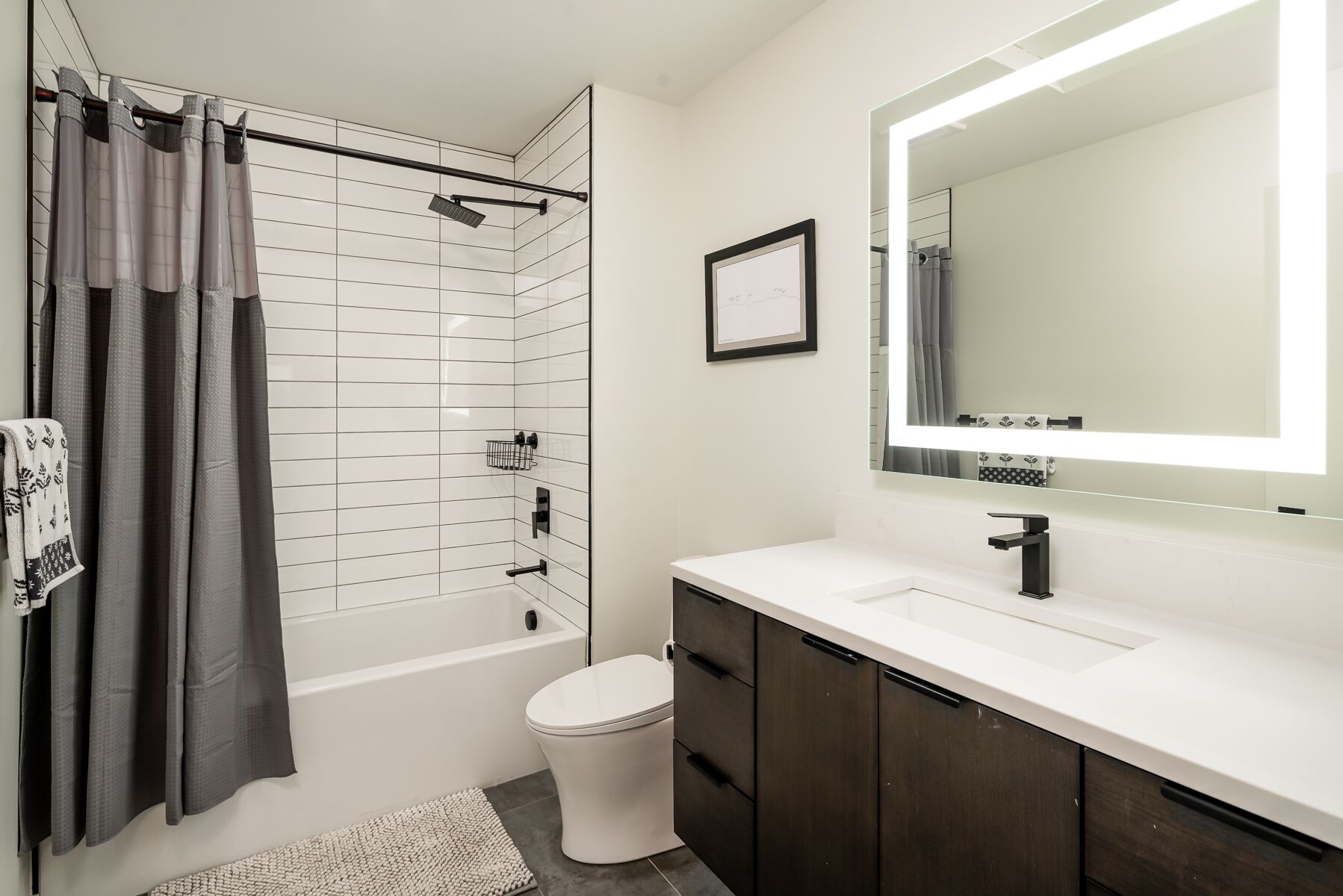 A modern bathroom with a bathtub, toilet, and vanity.