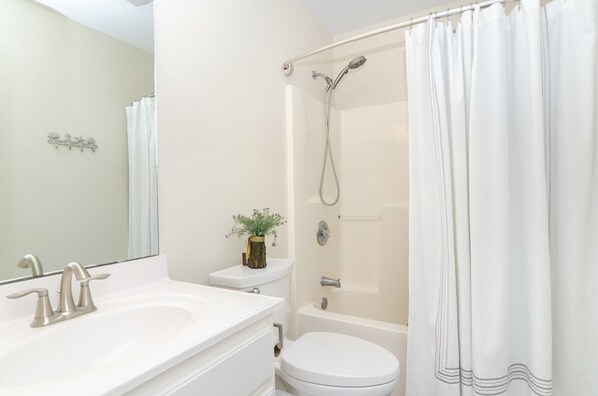 Un baño con lavamanos, inodoro y ducha blancos.