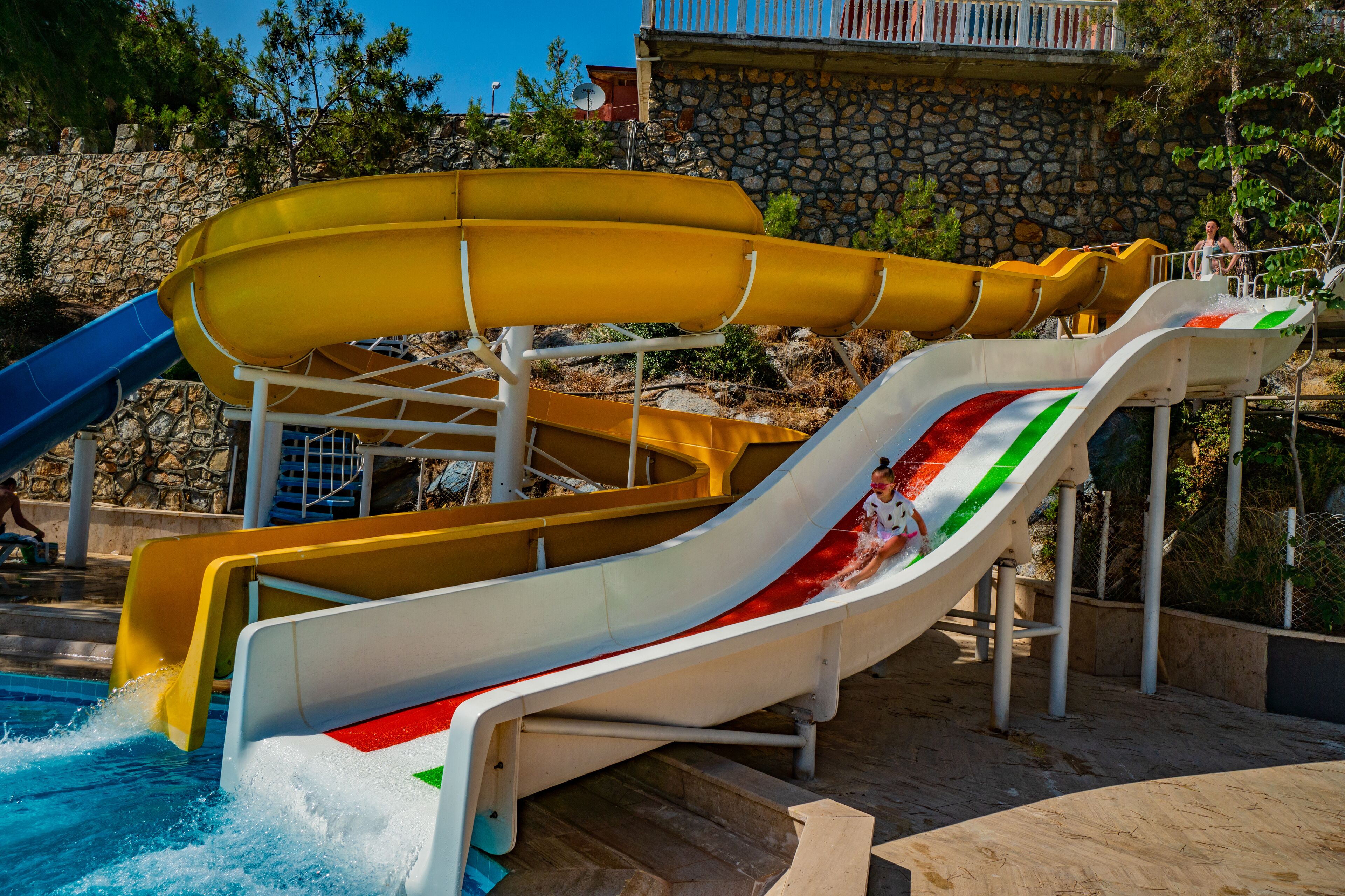 A water park with multiple slides, including a yellow and a white slide with red and green stripes.