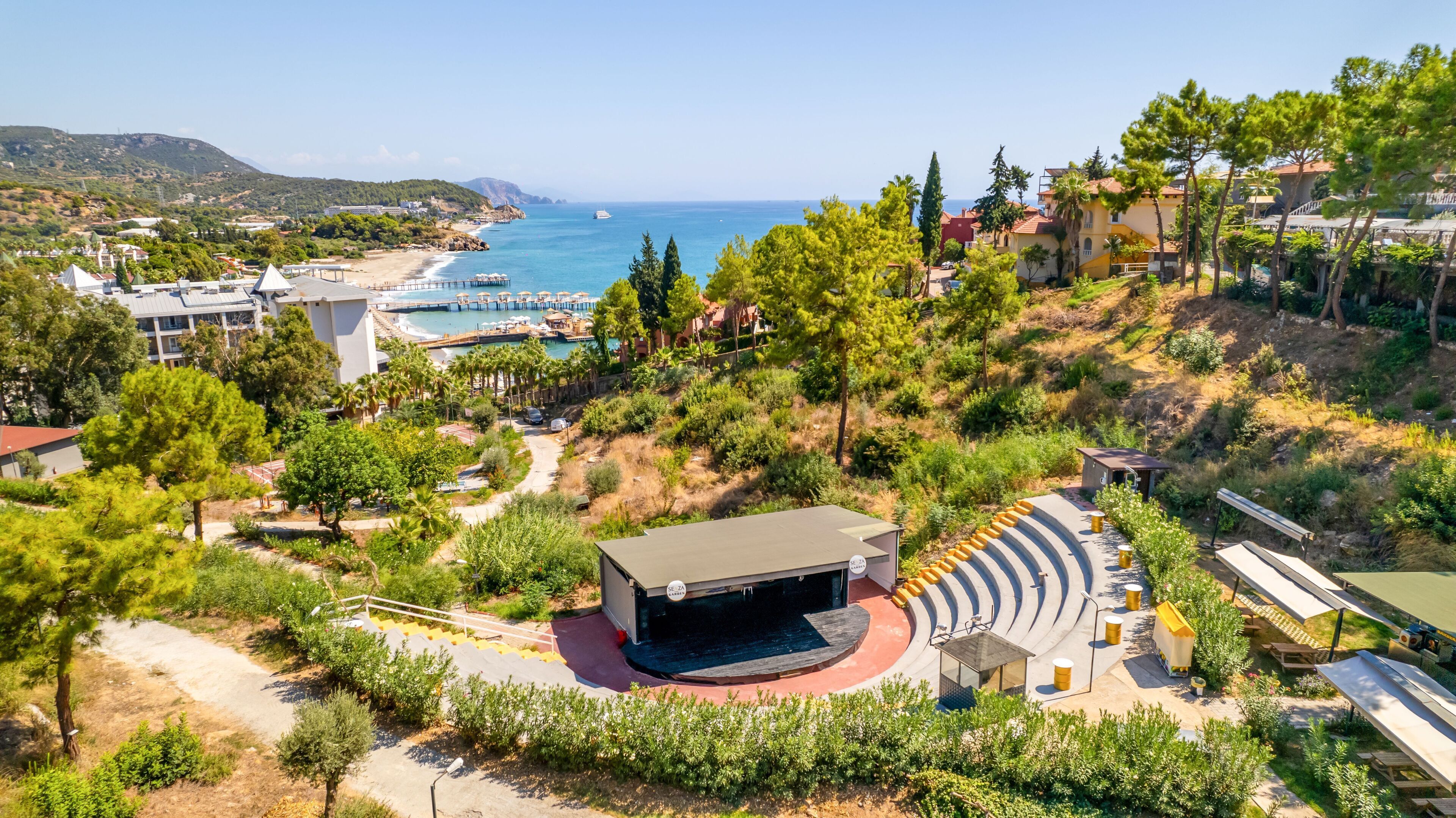 Ein Küstenresort mit Strand, Bühne und Poolbereich.