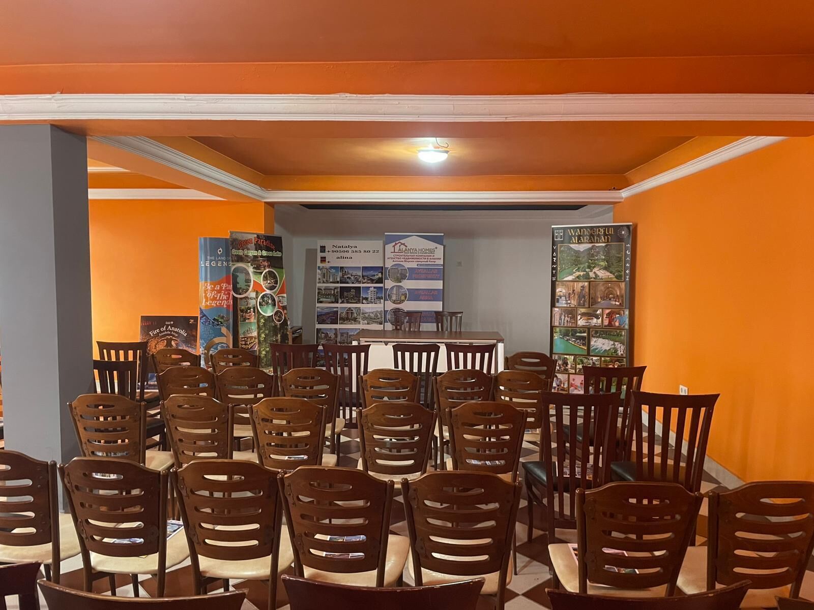 A dining area with multiple wooden chairs and tables, a counter, and informational posters on the walls.
