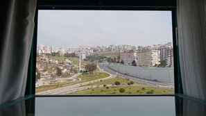 Vista a través de una ventana de un paisaje urbano con edificios residenciales, una autopista y un puente.