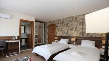 A hotel room with two beds, a desk, a chair, a mirror, and a patterned wall.