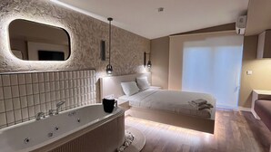 A modern bathroom with a freestanding bathtub, a large mirror, and a wooden floor. - Avwan Hotel Cigli (Izmir)