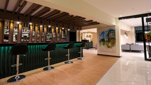 A bar area with wooden beams, a green accent wall, and four black bar stools. - Avwan Hotel Cigli (Izmir)