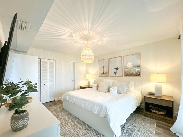 Un dormitorio con una cama grande, lámparas de noche, un candelabro y obras de arte en la pared.