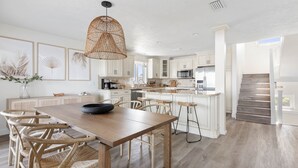 A spacious kitchen with a wooden dining table, white cabinetry, and a large island.