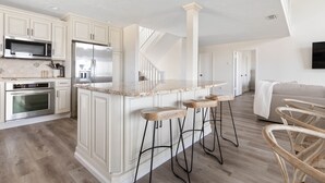 A modern kitchen with white cabinetry, stainless steel appliances, and a marble countertop.