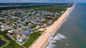 An aerial view of a coastal residential area with houses, a beach, and a body of water.