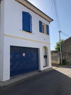Un immeuble de deux étages avec une façade blanche et des volets bleus.