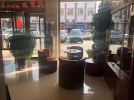 Un vestíbulo con un jarrón grande, una planta en maceta y un área de descanso con una mesa redonda y sillas.