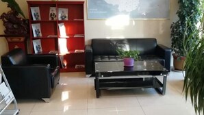 A lobby with a black leather sofa, a red bookshelf, and a map on the wall. - Greentree Inn Xinzhou Jianshe Road Express Hotel (Xinzhou)