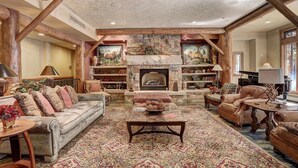 A spacious living room with a fireplace, wooden beams, and a large rug. - 3059 The Timbers 2 Bedroom Condo by RedAwning (Keystone)