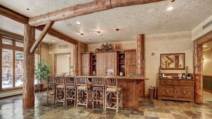 A rustic interior with a stone-tiled floor, wooden furniture, and a large wooden cabinet. - 3059 The Timbers 2 Bedroom Condo by RedAwning (Keystone)