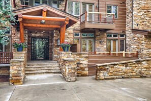 A stone building with a wooden entrance, a balcony, and a stone staircase. - 3059 The Timbers 2 Bedroom Condo by RedAwning (Keystone)