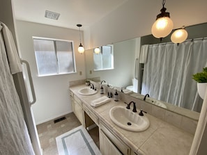 Un baño moderno con dos lavamanos, un espejo grande y una cortina de ducha.