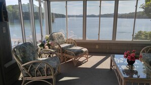 A room with wicker chairs and a glass table, overlooking a lake with distant hills. - Amazing! Tellico village lake house with dock! (Loudon)