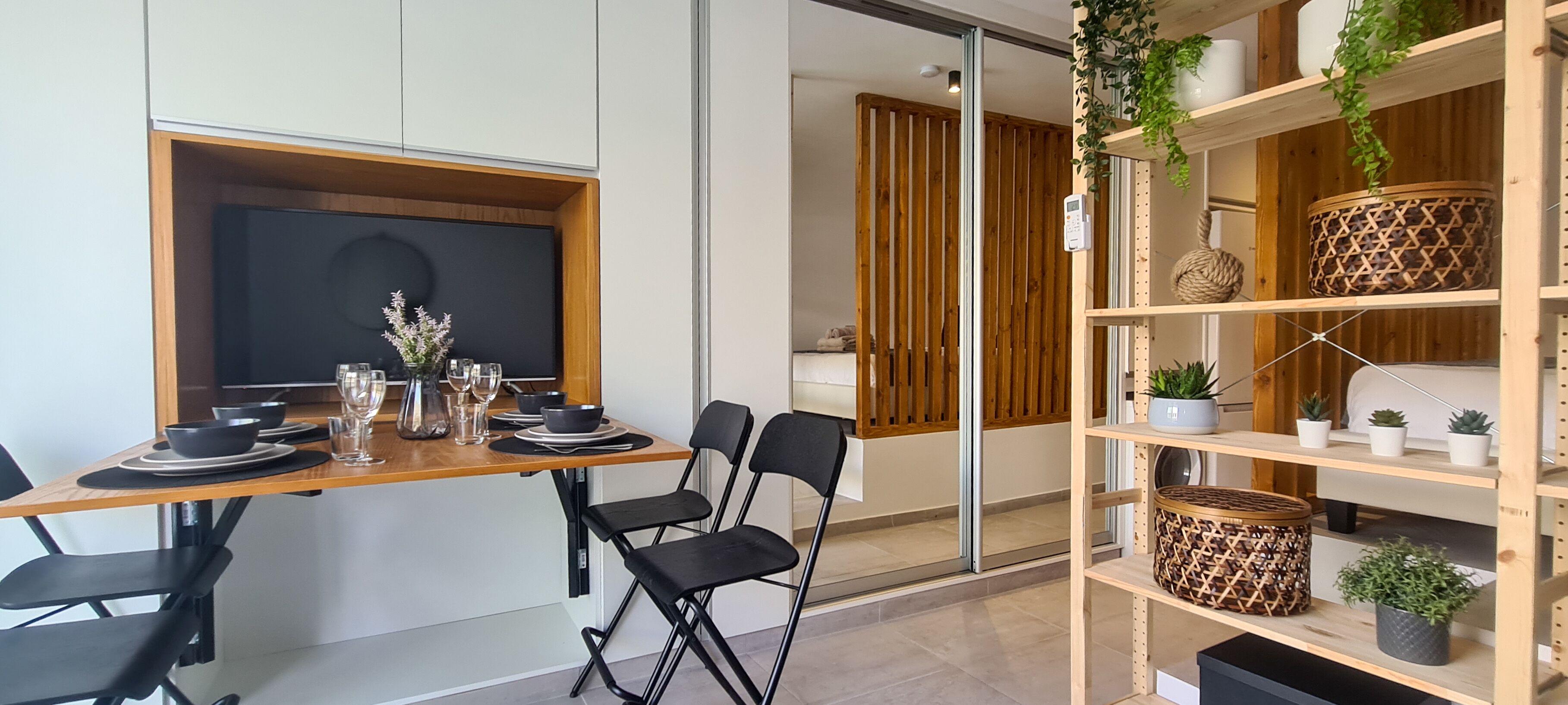 Een moderne eetruimte met een houten tafel gedekt voor vier personen, zwarte stoelen en een groot raam.