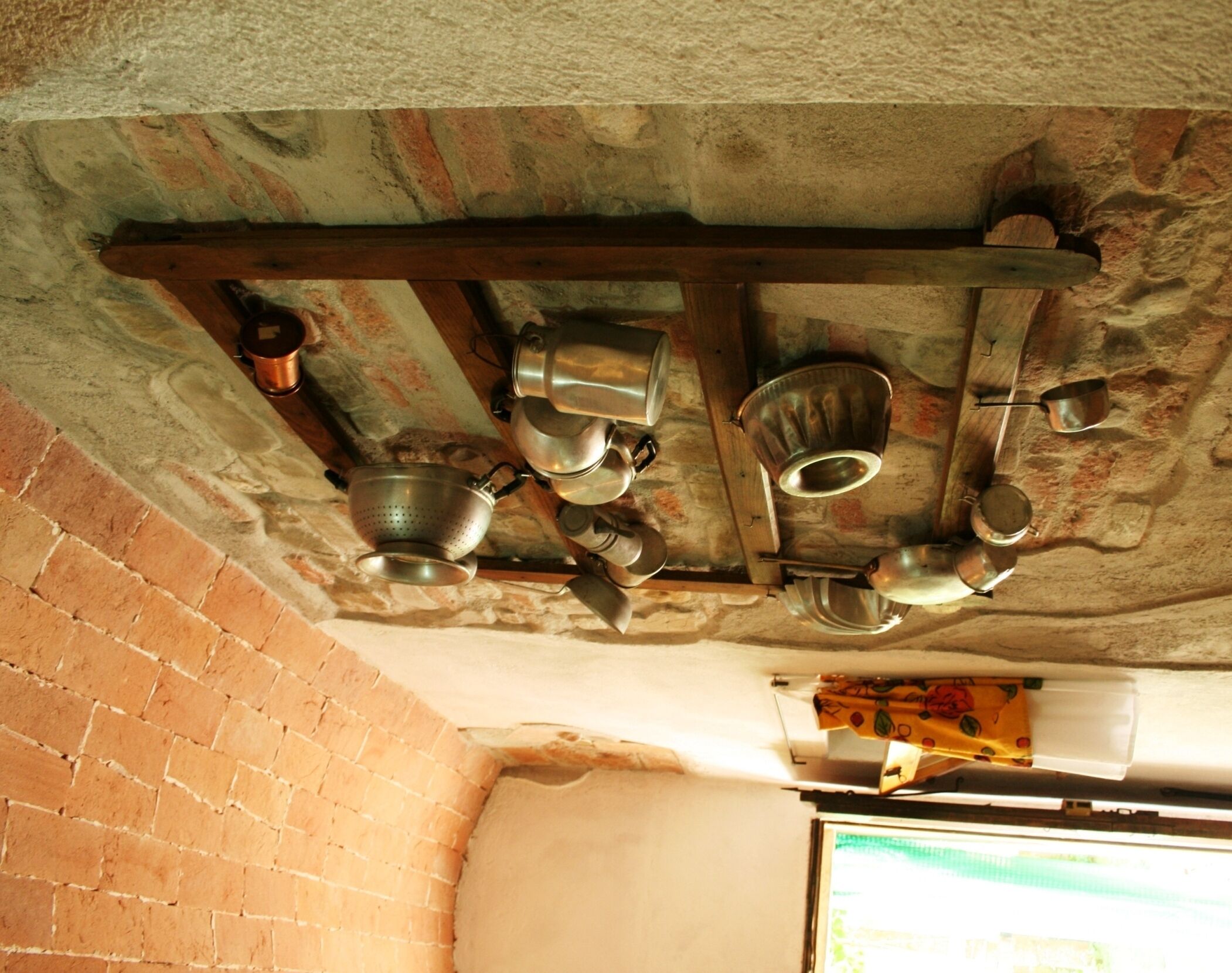 Une cuisine avec un mur en briques et un plafond avec une poutre en bois.