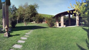 Un jardin bien entretenu, agrémenté d’une pergola en briques, d’un escalier en pierre et d’une variété d’arbres et d’arbustes.