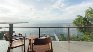 Terraço com mobiliário de madeira com vista para um corpo d'água e vegetação.