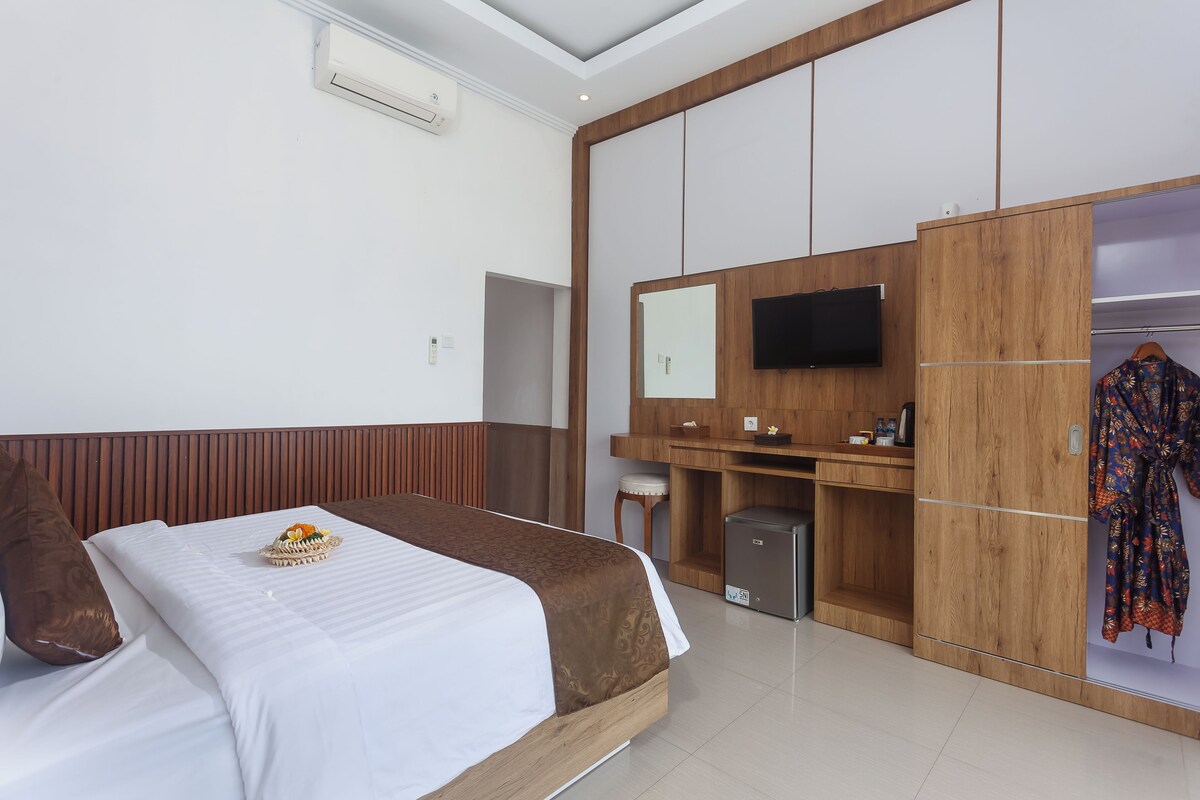 A modern hotel room with a bed, a desk, a wardrobe, and a television.