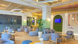 Un moderno vestíbulo de hotel con sofás, sillones, una mesa de centro y una planta grande en maceta.