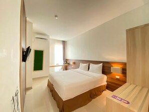 A hotel room with a large bed, bedside tables, a desk, and a chair.