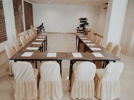 A conference room with a long table, chairs, and a plant.