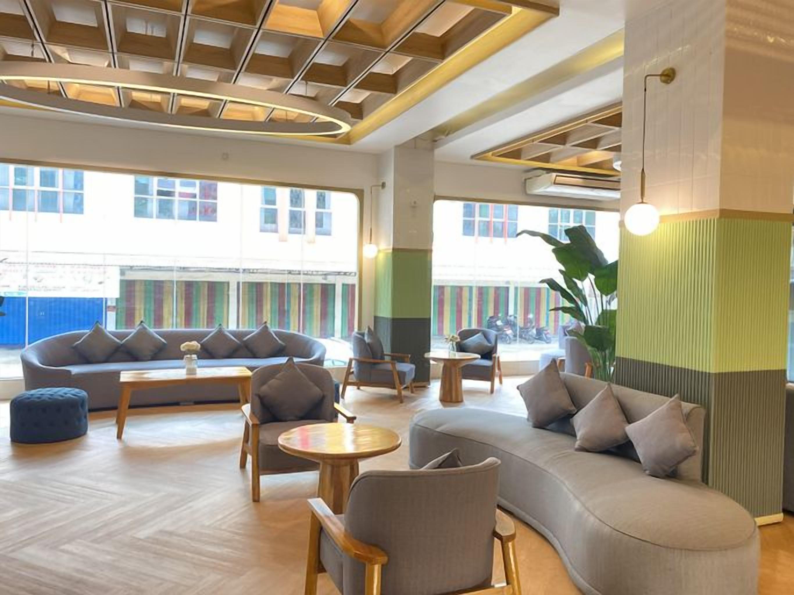Un espace de détente moderne avec un canapé incurvé, des tables rondes et des sièges confortables.