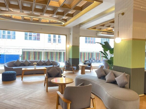 A modern lounge area with a curved sofa, round tables, and comfortable seating.