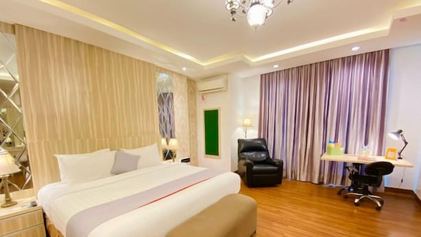 Una habitación de hotel con una cama grande, un escritorio, una silla y un candelabro.