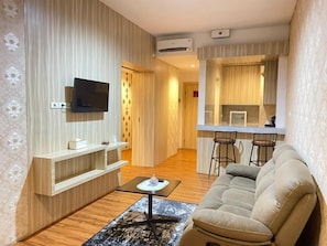 Uma sala de estar moderna com um sofá, uma mesa de centro e uma TV fixada na parede.
