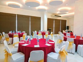 A conference room with round tables, white chairs, and red tablecloths.