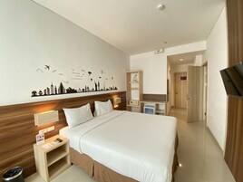 Habitación de hotel moderna con una cama grande, mesitas de noche, un televisor y un cuadro con un paisaje urbano.