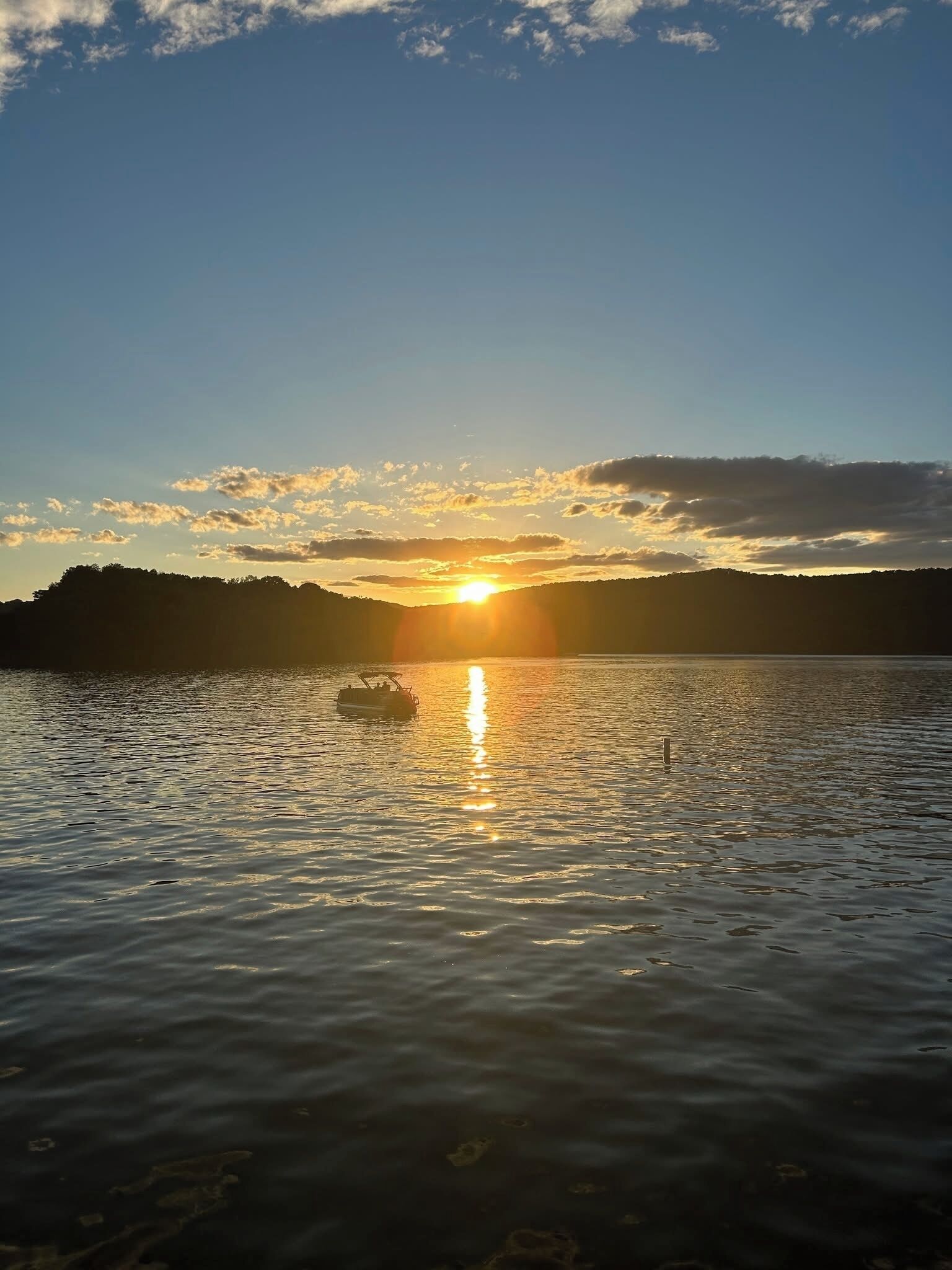 A sunset over a calm lake with a boat in the foreground.