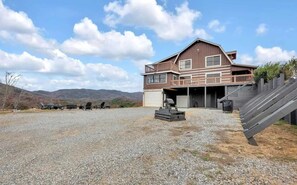A two-story house with a covered garage, a gravel driveway, and a wooden deck.