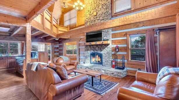 A log cabin interior with a stone fireplace, leather sofas, and wooden beams. - 5,000 Sq Ft 5BR/4.5BA Cabin, 20Min to Pigeon Forge (Sevierville)
