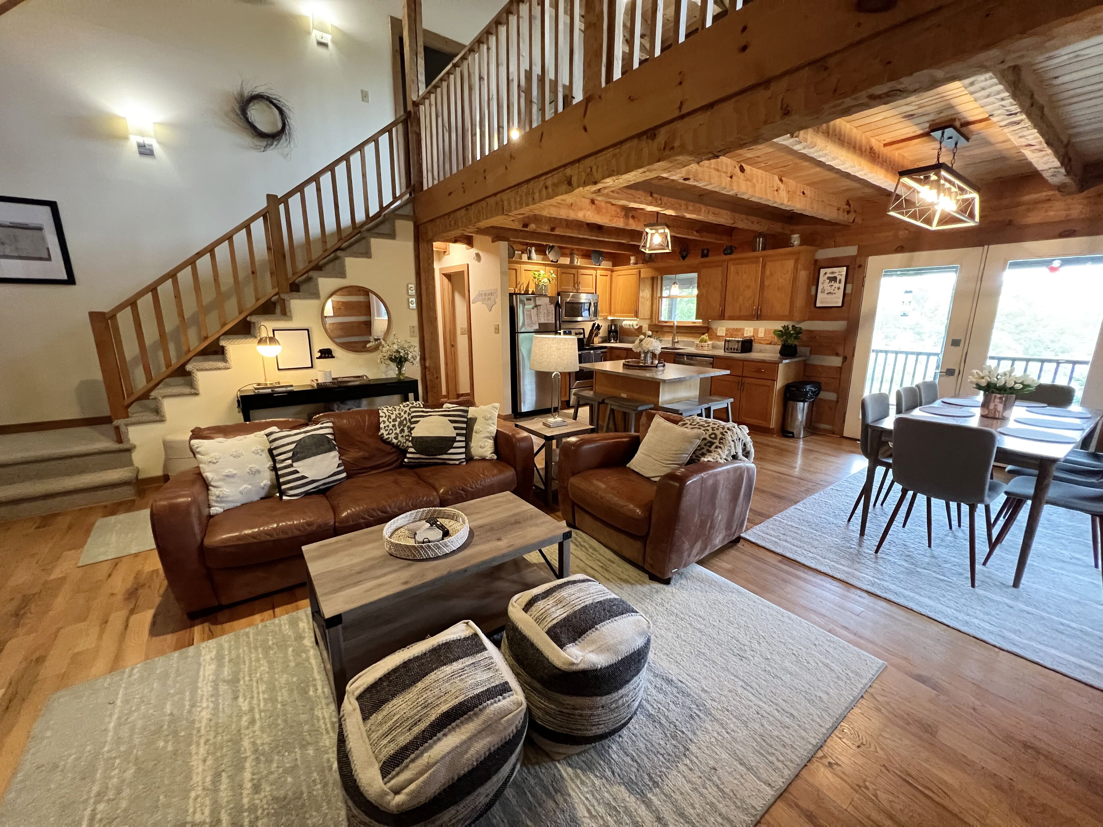 A spacious living area with a wooden staircase, a kitchen with wooden cabinets, and a dining area with a table and chairs.