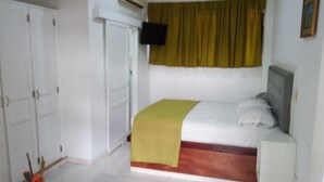 A bedroom with a bed, a bedside table, a wardrobe, and an air conditioning unit. - Quiet and comfortable room in the center. B&B (Santo Domingo)