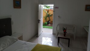 A hotel room with a bed, a desk, a chair, and a view of an outdoor area with plants and a door. - Quiet and comfortable room in the center. B&B (Santo Domingo)