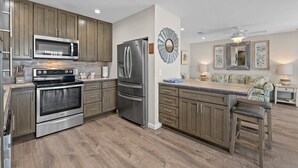 Una cocina moderna con electrodomésticos de acero inoxidable, armarios de madera y una isla central con taburetes de bar.