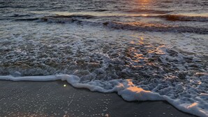 Una playa con olas y un atardecer.