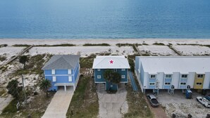 Propiedad costera con vista a la playa, que presenta un edificio azul con una estrella roja, un edificio blanco y un estacionamiento.